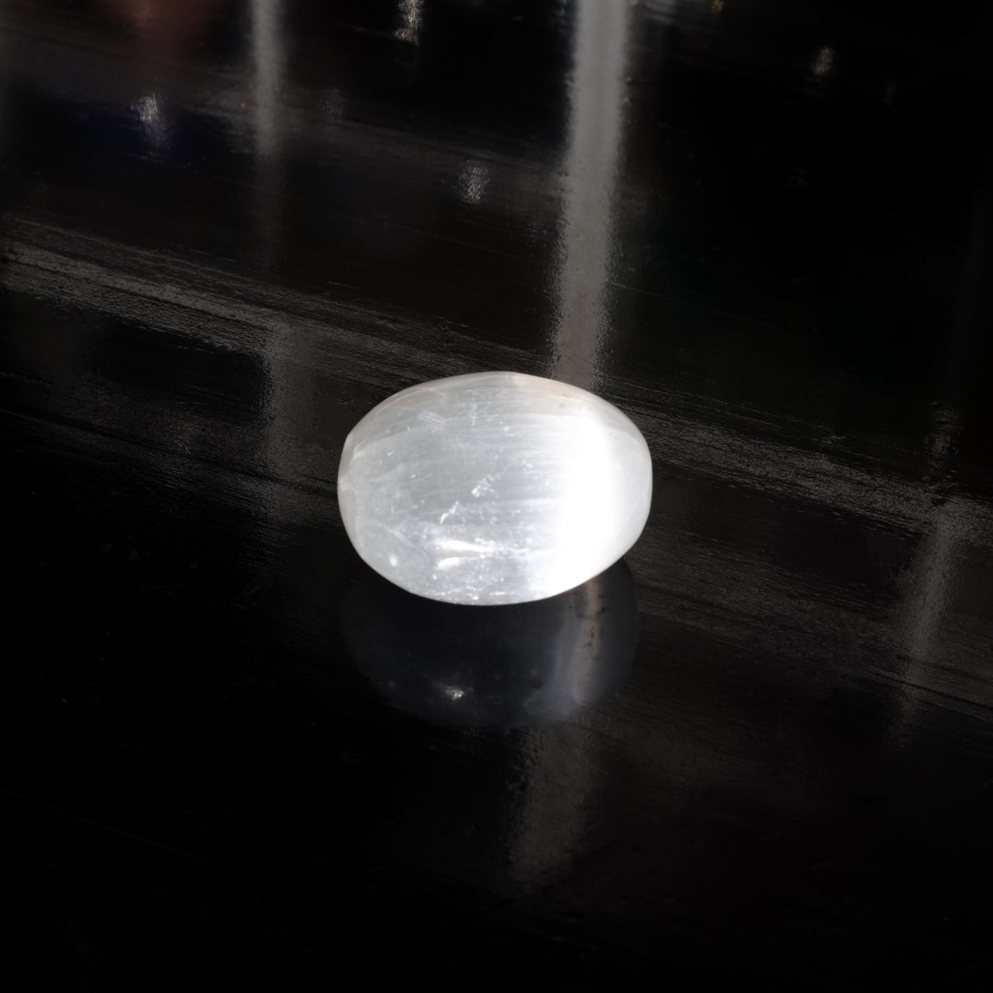 Pierre roulée en sélénite du Maroc de qualité AA, de couleur blanche translucide et de forme ronde, éclairée par la lumière du soleil.