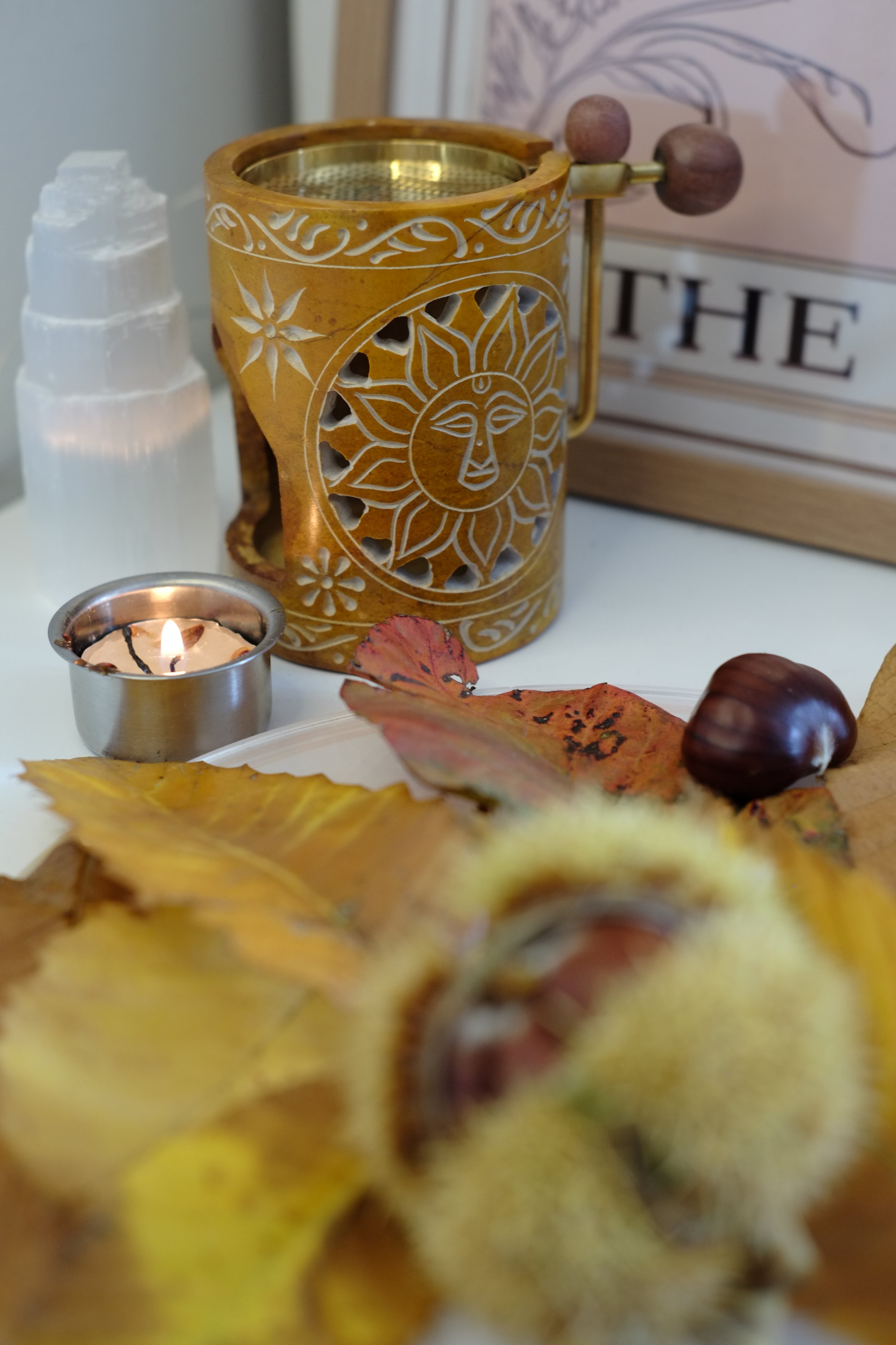 Décor automnal avec les lettres de Scrabble qui épellent "Hello Autumn", des feuilles mortes, des citrouilles, des pommes de pin et des bâtons de cannelle sur un fond noir style ardoise.