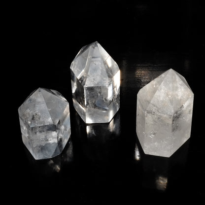 Pointes polies en cristal de roche du Brésil de qualité AA+ sur fond noir éclairés par la lumière du soleil.