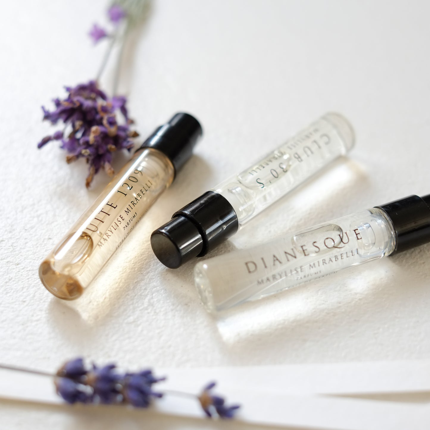Le Set Découverte composé de 3 mini flacons en format 2ml disposé sur une table blanche accompagné de 3 brins de lavande et de touches à sentir.