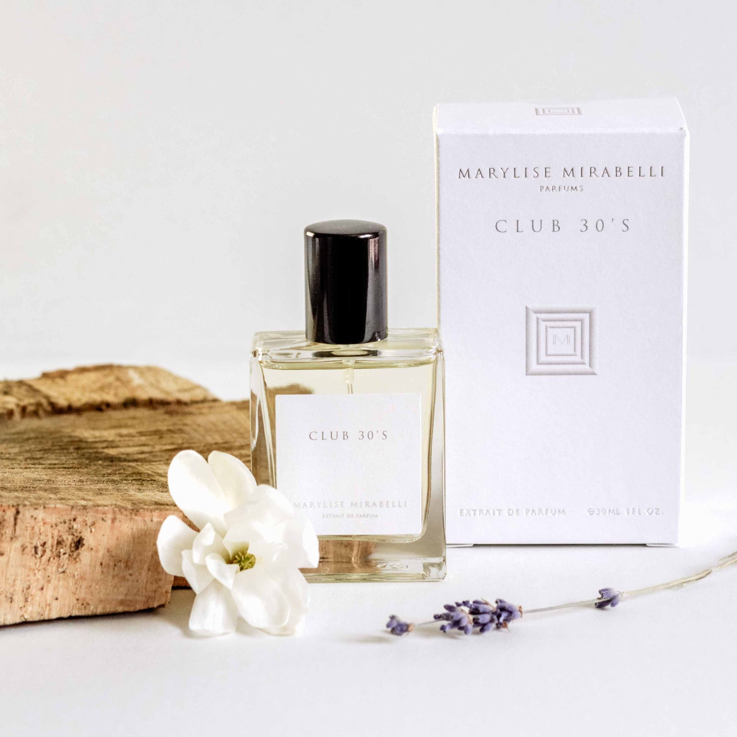 Petit flacon de parfum posé sur une table blanche à côté de sa boite. Le flacon de 30ml est rectangulaire avec une étiquette blanche, l'inscription Club 30's  et un bouchon noir brillant. La boite est blanche avec le logo carré au centre et les inscriptions Marylise Mirabelli parfums et Club 30's en haut. Une fleur blanche et un brin de lavande son posés délicatement à côté du flacon qui est adossé sur un morceau de bois clair.